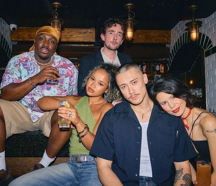 Group of young friends posing for a photo in a trendy bar setting