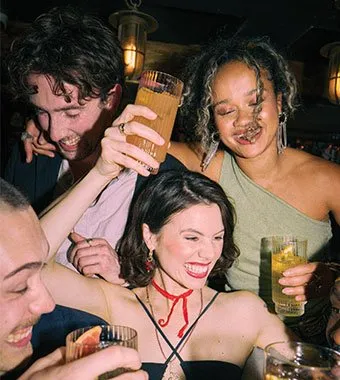 Group of young trendy friends dancing with whiskey drinks in their hands