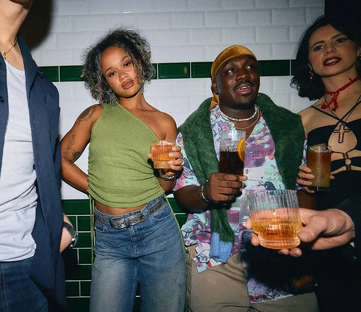 Group of young friends standing with glasses of mixed whiskey drinks